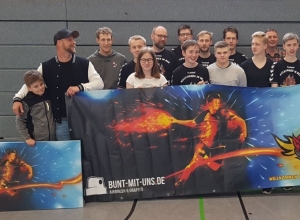 Graffiti- und Airbrushkünstler Maximilian Ziegner (2.v.l.) überreichte dem HF-Fanclub das von ihm entworfene Banner, das die Einheizer jetzt optisch in der Emssporthalle unterstützt. (Foto: Handballfreunde)