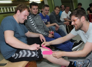 Pinkes Kinesio-Tape für das Keeper-Knie: Physiotherapeut Dennis Klück (r.) zeigt am Knie von Kreisliga-Torhüter Nico Quadflieg, wie ein Knie beklebt wird. Foto: hri